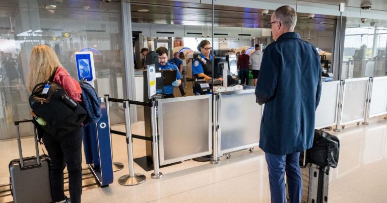 Passengers queuing at airport check-in counter with luggage, modern gate area with staff processing travelers